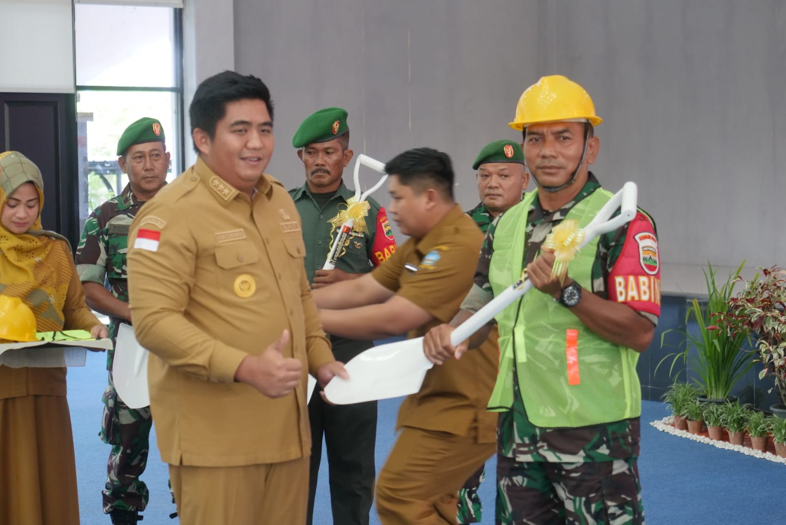 Bupati Bintan Roby Kurniawan menyerahkan skop ke Babinsa sebagai tanda dimulainya Program Karya Bhakti Pembangunan RTLH.